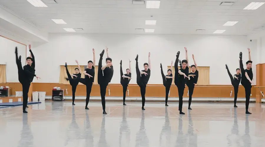 Dancers rehearsing synchronised extensions in an empty theatre